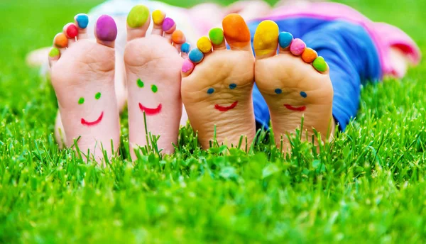 Children\'s feet with a pattern of paints smile on the green grass. Selective focus.child