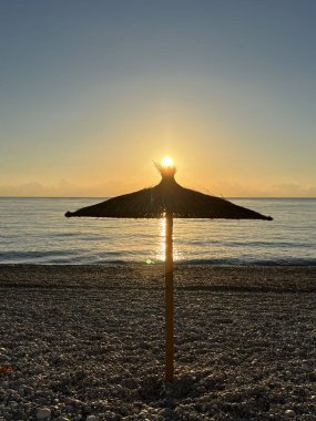 Albir İspanya plajında gün doğumuyla birlikte güneş şemsiyesi