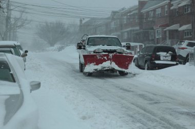 New York 'un varoşlarında yoğun bir kar fırtınası sırasında bir kamyonette kırmızı kar küreme aracı.