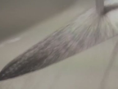 Woman washing shiny silver metal kitchen knife with small rust spots in kitchen sink. Extreme close up, 3:4, blurred and shaky.