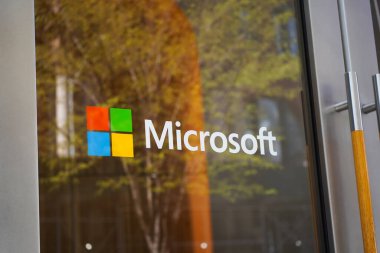 New York, New York - 9 Nisan 2023: Microsoft logosu Soho Manhattan 'ın cam kapısında yeşil ağaç yansımalı.
