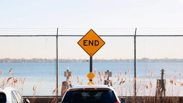 Symmetrical END of the road sign with fence and barbed wire at the sea shore