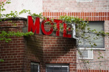Kırılmış ve harap olmuş kentsel kırmızı MOTEL tabelası ve aşırı büyümüş bitki örtüsü