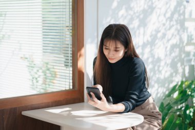 Asyalı çalışan kadın cep telefonuna mesaj atıyor, sohbet ediyor, sosyal medya kullanıyor. İş kadını akıllı telefon web sitesi, e-kitap okumak, hisse senedi ticareti ve arama işi kullanır. İletişim teknolojisi.