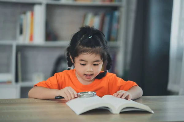 Азійська Дівчинка Яка Тримає Збільшуюче Скло Над Книжкою Читає Книжкову — стокове фото
