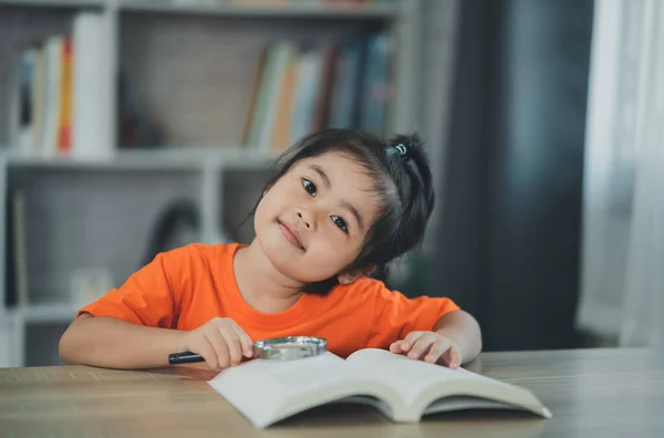 Азійська Дівчинка Яка Тримає Збільшуюче Скло Над Книжкою Читає Книжкову — стокове фото
