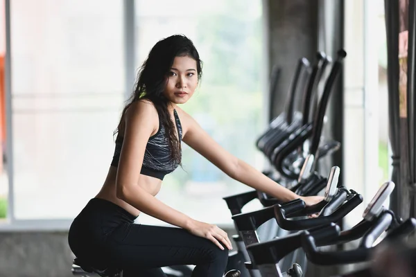 ジムで自転車に乗って運動するアジアのスポーツ女性は 体重を減らすことを決意し 彼女の健康を作ります 運動自転車女性フィットネススポーツのコンセプト — ストック写真