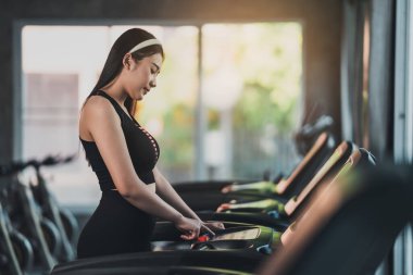 Sporcu Asyalı bayan sporcu spor koşucusu spor salonunda koşu bandında koşmadan önce başlama düğmesine bas. Kardiyo çalışması. Sağlıklı bir yaşam tarzı, spor salonunda kadın eğitimi. Spor çalıştırma konsepti.