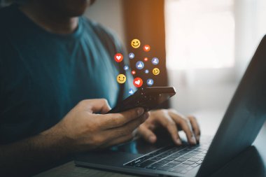 Sosyal medyada akıllı telefon sohbeti yapan serbest çalışan bir adam. Sosyal medya ve dijital online konsept. Konsept cep telefonu ekranda simge duygularıyla sosyal medya oynuyor. Sosyal Mesafe Kavramı.