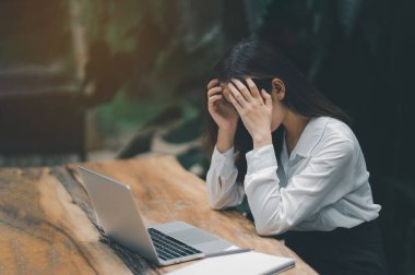 Asyalı serbest çalışan kadın evde dizüstü bilgisayarla çalışırken stresli depresyon geçiriyor. Bunalımlı kadın üzgün ciddi evde çalışıyor. Herhangi bir yerde çalışma kavramı.