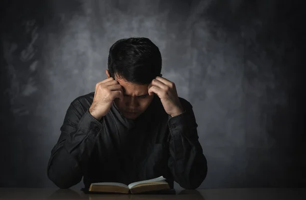 stock image Asian man reading book or bible hand over head having stressful depression sad time sitting on the table. Depression man sad serios reading book. Education learning bible religion concept.