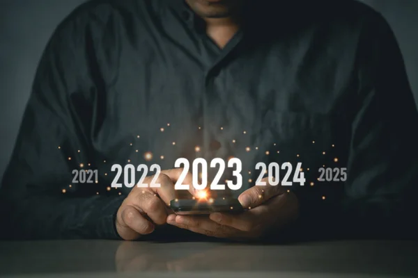 New Year 2023 concept. Start happy new year 2023. Businessman freelance investors using mobile phone touch screen virtual 2023 year diagram, business planning, strategy, business trends, investment.
