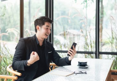 Akıllı telefona ve kutlamaya bakan iş adamı, neşeli ve başarılı iş adamı, cep telefonunu mornitor stok veya kripto para birimi veya kumarhane için kullanan iş adamı. Akıllı telefon görüşmesi konferansı.