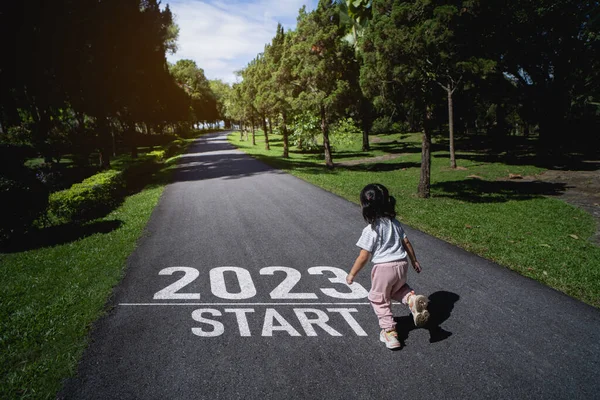 Asian baby running start into the new year 2023. Start up of runner woman running on nature race track go to Goal of Success. People running as part of Number 2023. Sport health care.