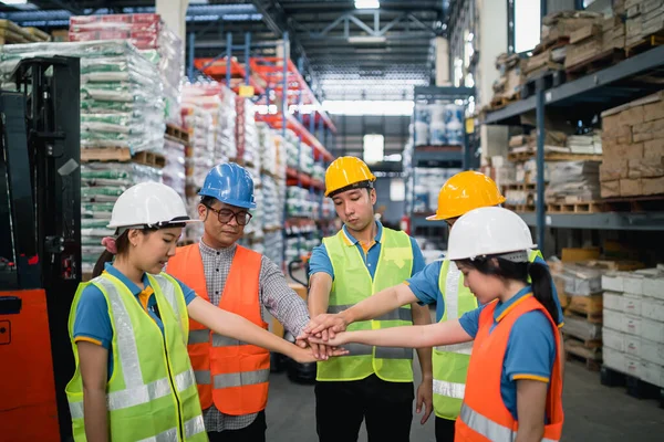 Group of industrial warehouse asian engineer or worker in safety suite hand stack celebrate successful or deal commitment. Logistics, supply chain, warehouse business.Teamwork unity under view concept