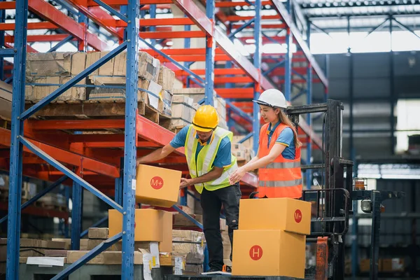 Asian warehouse workers or engineer man and woman lifting  box of goods to place on the shelf and standing on floklift in warehouse factory store, worker counting check stock. Warehouse Logistic.