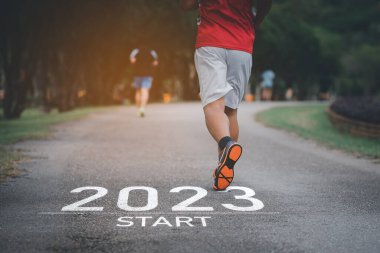 Parkın bahçesinde koşan sporcu. 2023 yılına başla. Doğa yarış pistinde koşan koşucu kadınla başla. Başarının Hedefi 'ne git. 2023 numaranın bir parçası olarak koşan insanlar. Spor sağlık hizmetleri.