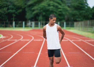 Athletes sport man runner wearing white sportswear to stretching and warm up before practicing on a running track at a stadium. Runner sport concept.