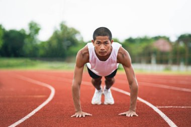 Sporcular spor kıyafetlerini giyip spor kıyafetlerini giyerek bir stadyumdaki koşu pistinde antrenman yapmadan önce ısınıyor ve ısınıyor. Sporcu sporcu, yarışma için antrenmana hazır ol..