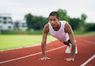 Sporcular spor kıyafetlerini giyip spor kıyafetlerini giyerek bir stadyumdaki koşu pistinde antrenman yapmadan önce ısınıyor ve ısınıyor. Sporcu sporcu, yarışma için antrenmana hazır ol..