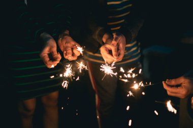 Yeni yılınız kutlu olsun ve mutlu noel ailesi, parlak ışık kavramına sahip, yanan bir havai fişek feneri tutan, parıldayan karanlık eli olan yakın bir kadın. Yeni yıl kavramı.