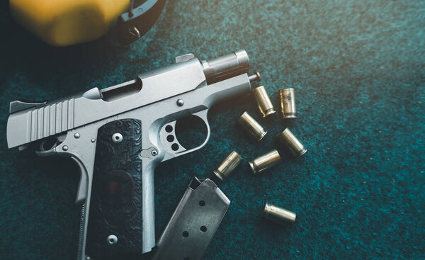 Вид сверху, плоская раскладка пистолетных пуль и желтый шум, гасящий наушники на бумажной тренировочной мишени. После того, как стрелок потренировался стрелять на стрельбище. Концепция спортивной стрельбы.