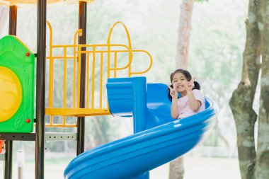 Cute asian girl smile play on school or kindergarten yard or playground. Healthy summer activity for children. Little asian girl climbing outdoors at playground. Child playing on outdoor playground.
