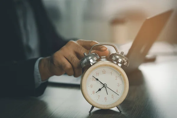 自宅での期限 時間管理の概念のために残業を働くためにラップトップを使用してビジネスマンの近くの机の上に目覚まし時計の選択的な焦点 ビジネスコンセプト — ストック写真