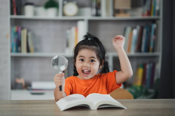 Ασιατικό Κοριτσάκι Κρατώντας Μεγεθυντικό Φακό Και Σηκώστε Χέρι Σας Διαβάζοντας — Φωτογραφία Αρχείου