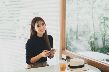 Asyalı çalışan bir kadın cep telefonuna mesaj atar, sohbet eder ya da sosyal medya kullanır. İş kadını akıllı telefon web sitesi kullanır, e-kitap okur, hisse senedi satar. İletişim teknolojisi kavramı.