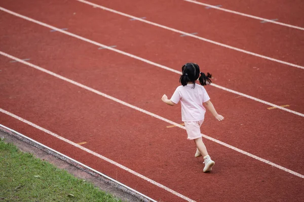 stock image Baby asian girl run jogging at running track, running field at stadium. little girl running at sunset happy baby girl smiling. little girl running at sunset. cute baby girl running at running track.