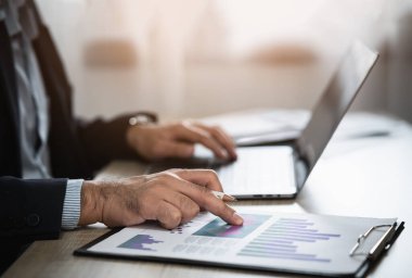 Serbest çalışan adamın kalem noktası çizelgesini kullanırken çekilmiş resmi ve evdeki masada dizüstü bilgisayarla çalışıyor. İşletme bürosunda çalışan bir girişimci. Ev konseptinde iş çalışması.