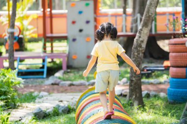 Arka taraf. Asyalı kızlar okulda, anaokulunda ya da çocuk parkında oynarlar. Çocuklar için sağlıklı bir yaz aktivitesi. Küçük Asyalı kız çocuk parkında dışarı tırmanıyor. Çocuk dışarıda oyun oynuyor..