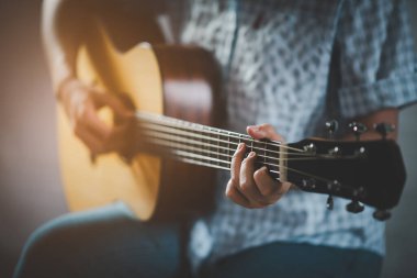 Kadın halka açık bir parkta akustik gitar çalıyor. Ağacın altında mutlu bir şekilde gitar çalan kadın..