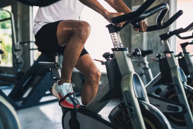Spor salonunda bisiklet üzerinde egzersiz yapan Asyalı sporcunun bacaklarını kapat. Kardiyo yapma azmi onu sağlıklı kılıyor. Egzersiz bisikleti sporu konsepti.