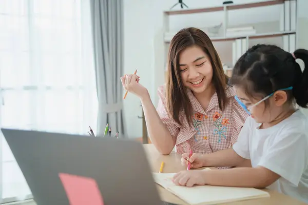 Азіатська Мати Навчає Дівчинку Окулярах Робити Вдома Використовуючи Ноутбук Записувати — стокове фото