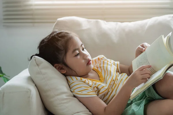 Радісна Щаслива Азіатська Дівчинка Дитина Посміхається Читає Книгу Сидячи Дивані — стокове фото