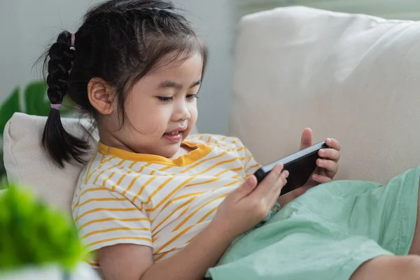Азіатська Дівчинка Дивиться Допомогою Торкається Екрану Мобільного Телефону Дивані Дитина — стокове фото