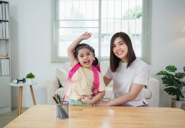 Ebeveynler ve Asyalı anaokulu öğrencileri pembe okul çantalarını hazırlayıp derslere başlamak için okula gidiyorlar. Heyecanlı kız ve anne okula döndükleri için mutlular..