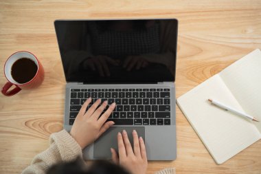 Üst Manzara. Klavyeye yazı yazan ve evdeki masada dizüstü bilgisayar kullanan Asyalı serbest çalışan bir kadın. Girişimci kadın işi için oturma odasında çalışıyor. İş yeri ev kavramı.