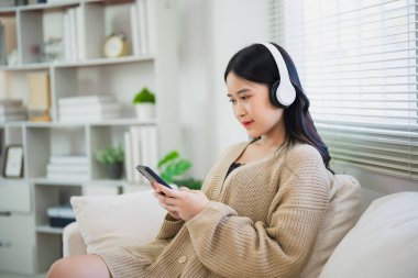 Asyalı serbest kadın gülümseyerek uzanıyor rahatlıyor, cep telefonu kullanıyor ve kulaklık takıyor kanepede müzik dinliyor. Girişimci kadın iş arıyor, hisse senedi ticareti yapıyor ya da internet oturma odasını karıştırıyor..