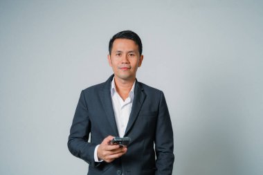 Gri arka planda seyyar stüdyo kullanan Asyalı iş adamı, genç işadamı yönetici ya da yönetici, gülümseyen ve kendinden emin olması olumlu bir başarı..