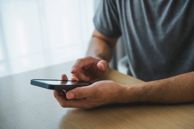 Masada dizüstü bilgisayarla çalıştıktan sonra akıllı telefon kullanan iş adamı, cep telefonunu arama yapmak için kullanan ya da sosyal medya veya online alışveriş yapan ya da stok ya da kripto para birimi kullanan adam. Akıllı telefon görüşmesi konferansı.