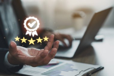 İş adamı elinde sanal bir ikon tutarak beş yıldızlı premium hizmeti sunuyor. Yüksek standartları olan el işçisi garanti, hizmet kalitesi, beş yıldız garantisi. Kaliteyi garantile.