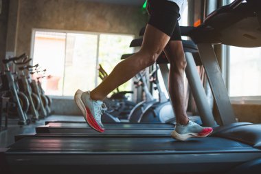 Ayaklarını kapat, spor koşucusu fitness kulübünde koşu bandında koşuyor. Kardiyo çalışması. Sağlıklı bir yaşam tarzı, spor salonunda antrenman yapan bir adam. Spor çalıştırma konsepti