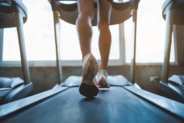 Close up of feet, sportman runner running on treadmill in fitness club. Cardio workout. Healthy lifestyle, guy training in gym. Sport running concept.