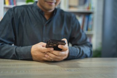 Masada dizüstü bilgisayarla çalıştıktan sonra akıllı telefon kullanan iş adamı, cep telefonunu arama yapmak için kullanan ya da sosyal medya veya online alışveriş yapan ya da stok ya da kripto para birimi kullanan adam. Akıllı telefon görüşmesi konferansı.
