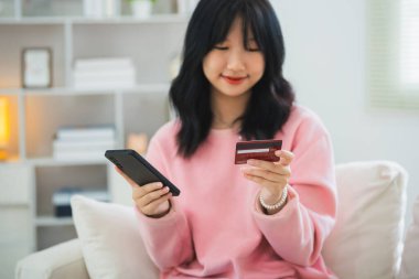 İnternetten alışveriş yapmak için cep telefonu akıllı telefonu kullanan bir kadın. Evde çalışan Asyalı kadın. Çevrimiçi alışveriş, e-ticaret, internet bankacılığı, harcama, ev konseptinden çalışma.