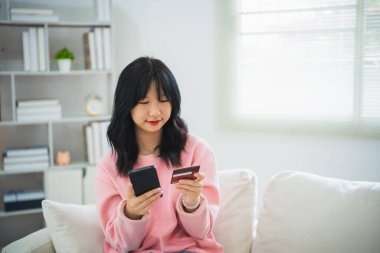 İnternetten alışveriş yapmak için cep telefonu akıllı telefonu kullanan bir kadın. Evde çalışan Asyalı kadın. Çevrimiçi alışveriş, e-ticaret, internet bankacılığı, harcama, ev konseptinden çalışma.