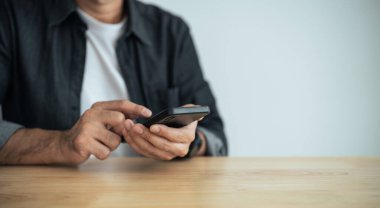 Masada dizüstü bilgisayarla çalıştıktan sonra akıllı telefon kullanan iş adamı, cep telefonunu arama yapmak için kullanan ya da sosyal medya veya online alışveriş yapan ya da stok ya da kripto para birimi kullanan adam. Akıllı telefon görüşmesi konferansı.